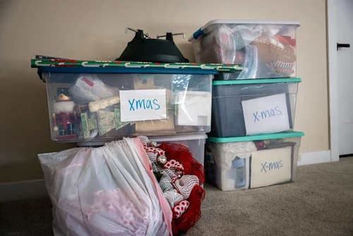 Plastic translucent storage totes labeled "XMAS" sitting on a carpet floor.