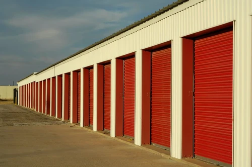 A row of red and white outdoor drive-up storage units.