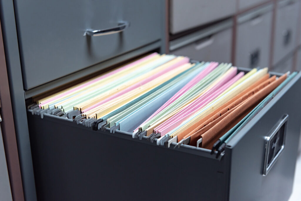 A filing cabinet with multicolored folders organized for document storage.